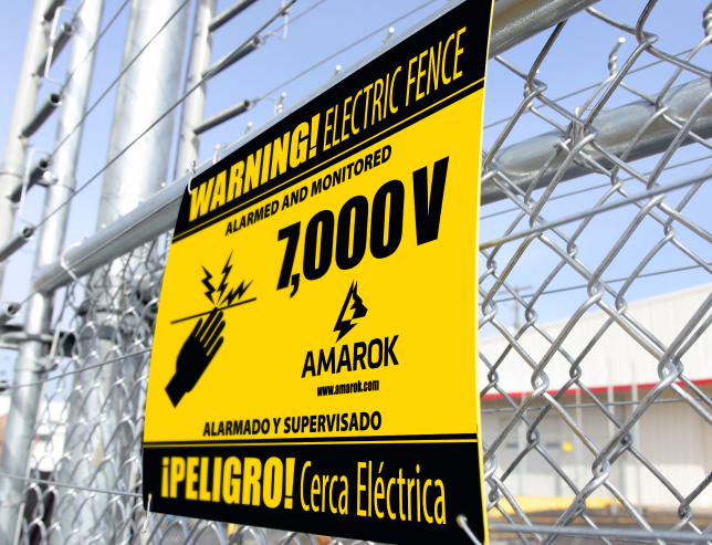A yellow sign on a chain link fence says "Warning Electric Fence"