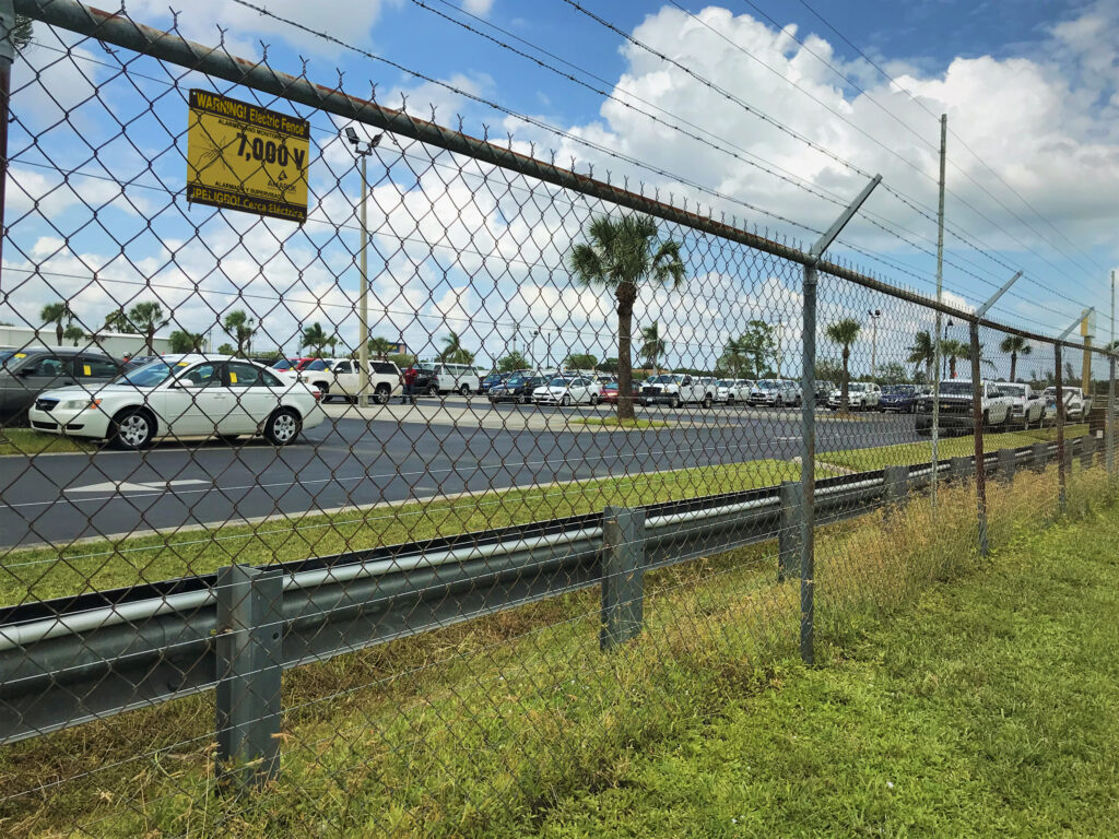 An electric chain link fence surrounding a parking lot