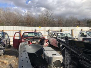 Cars at a junk yard surrounded by an electric fence