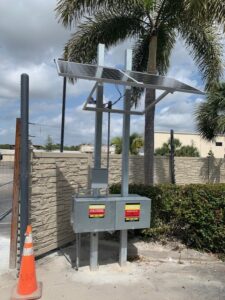 Electric Fence Powered By a Solar Panel with a Palm Tree in Background