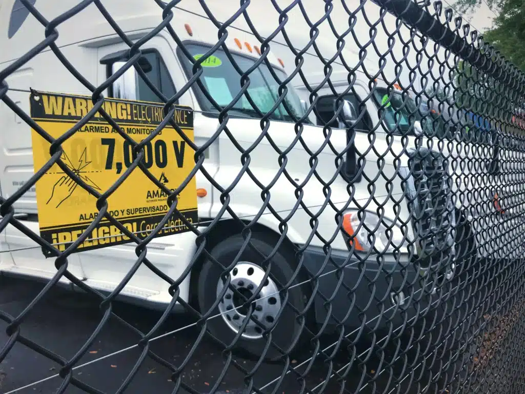 Trucks inside of fence with AMAROK voltage sign