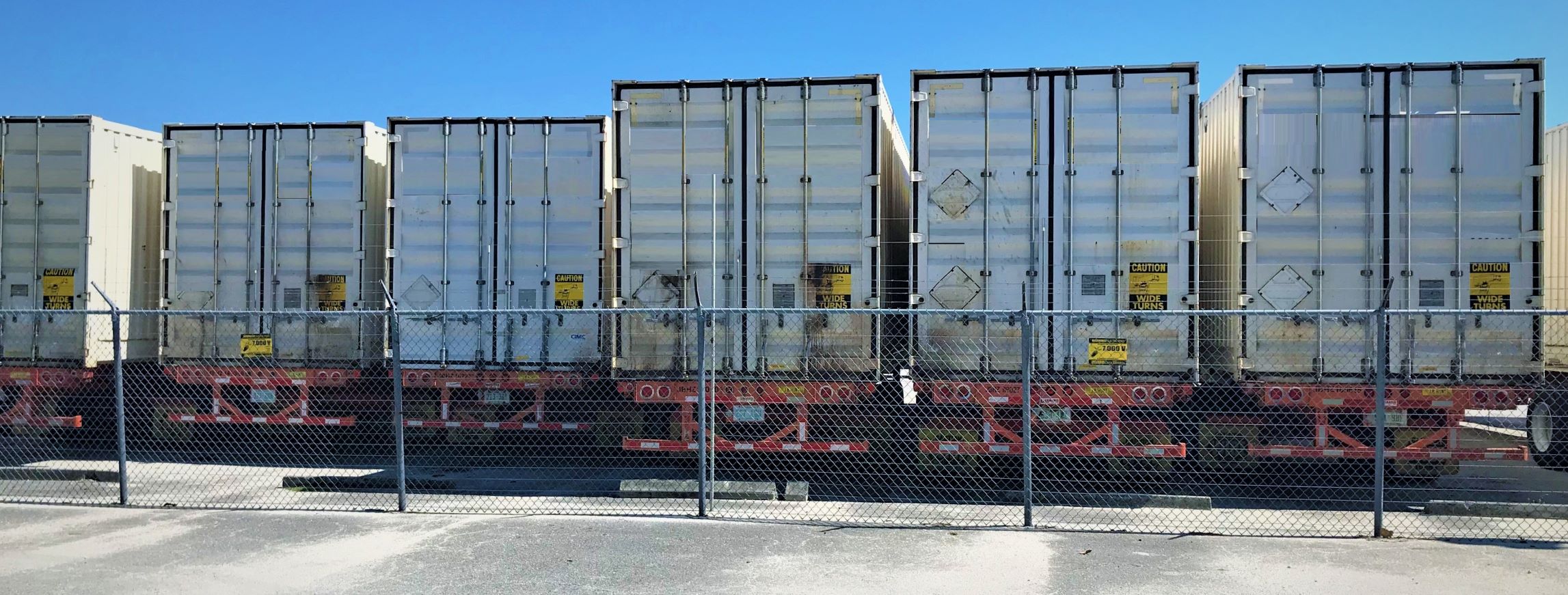 a row of shipping containers with caution signs on the doors