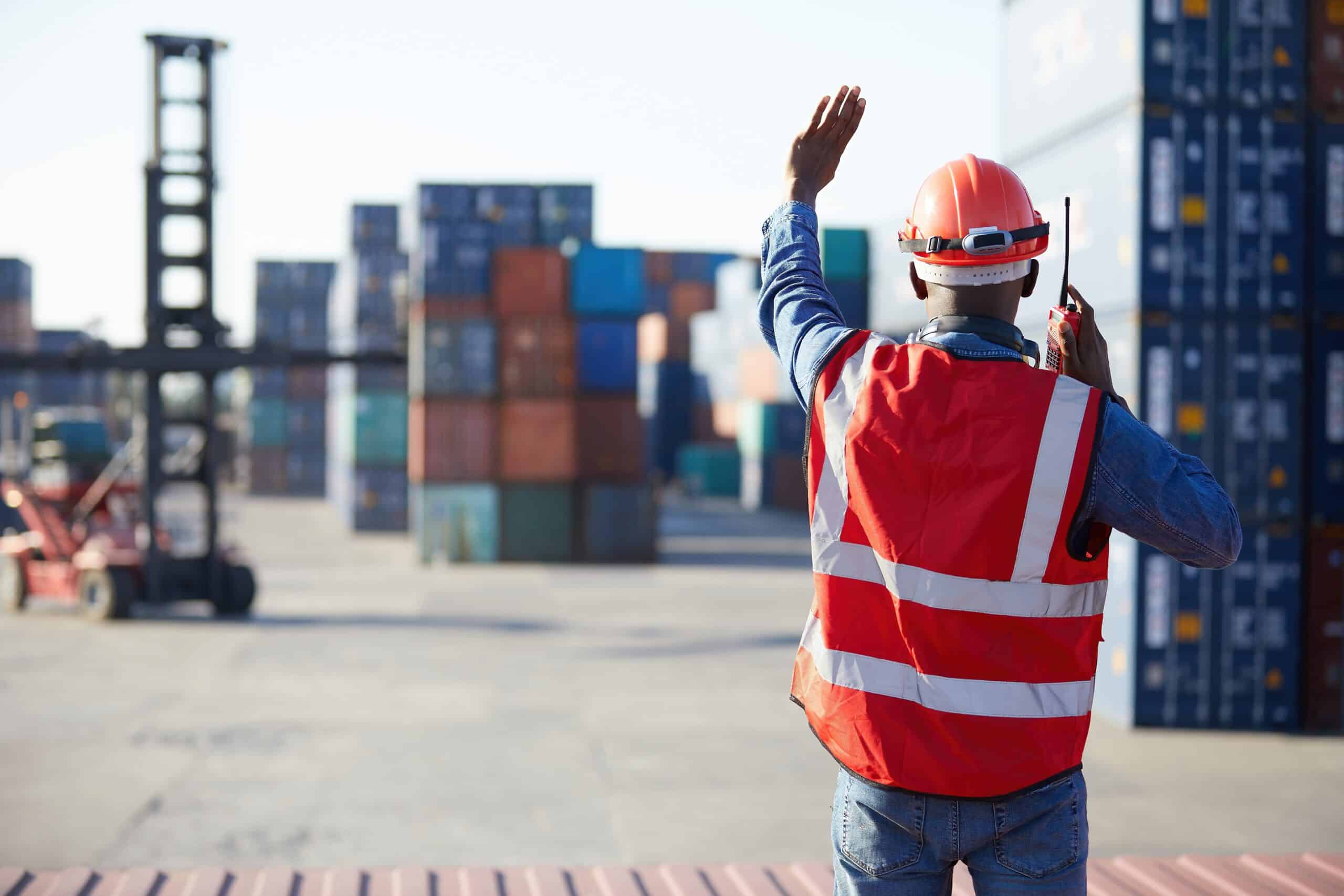 Worker Talking on a Walkie Talkie at a Shipping Container Lot