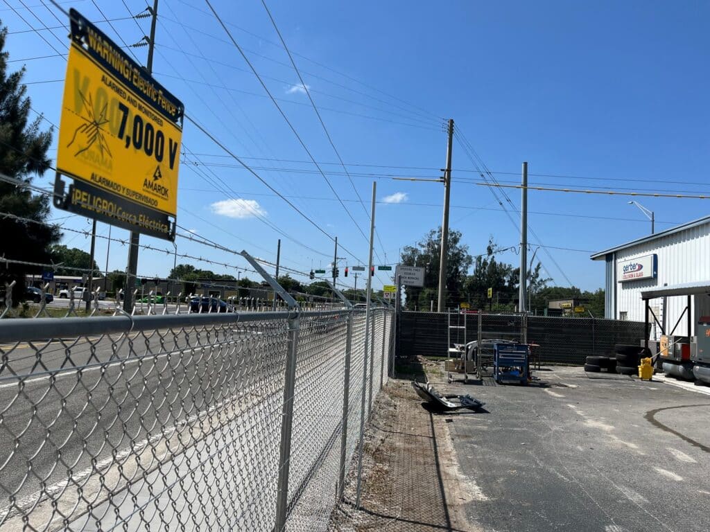 A Chain Link Fence With a Sign That Says Warning Electric Fence