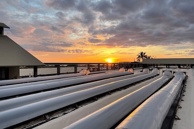 The Sun is Setting Behind a Row of Pipes