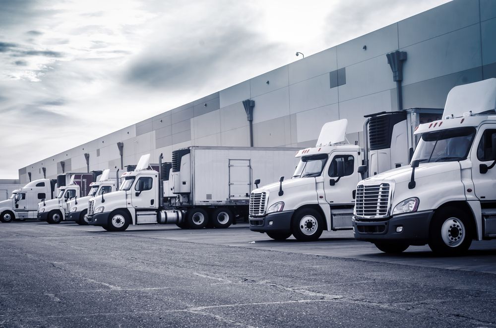 A row of semi trucks are parked in front of a building