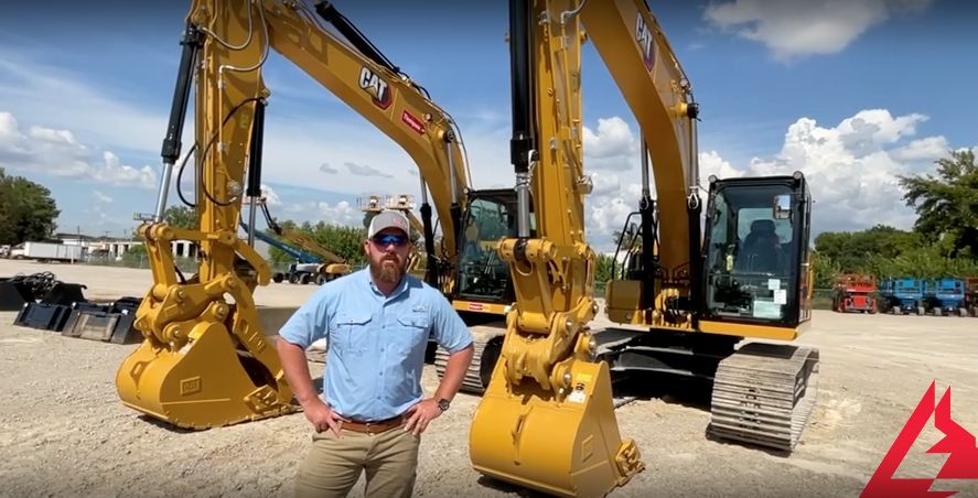 A man stands in front of a cat excavator